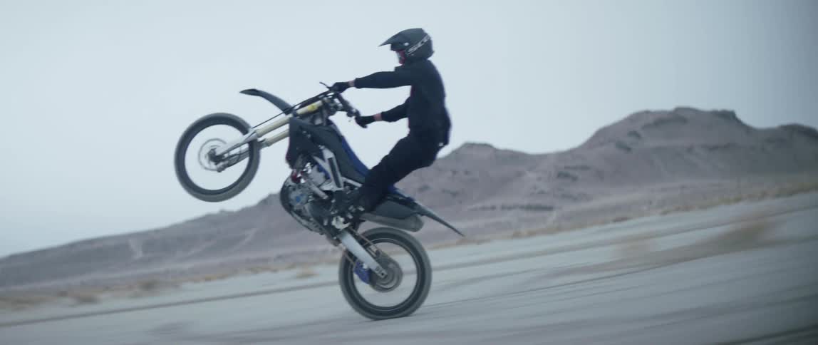 A person is doing a pop wheelie on a dirt bike