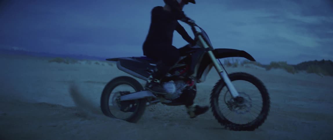 A rider turns his dirt bike in the sand