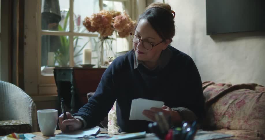 A woman takes notes while looking at photographs
