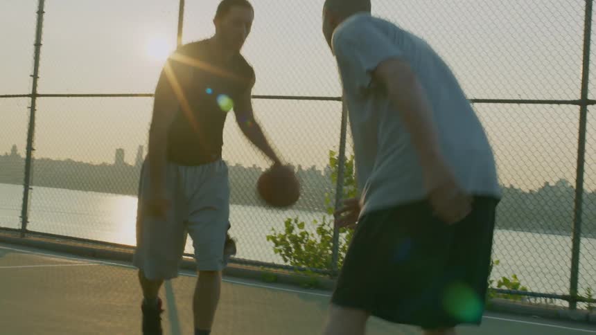 Two men play basketball on an outdoor court