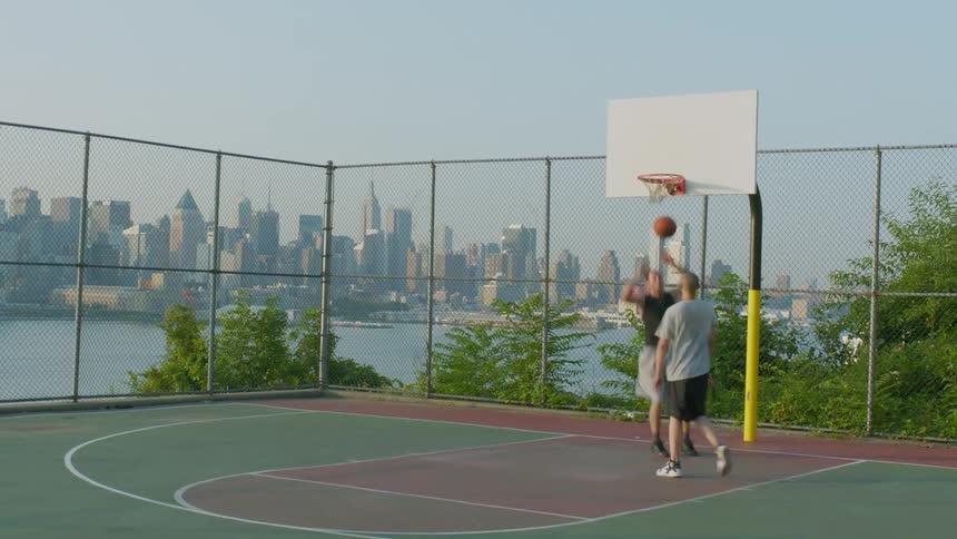 Two men play basketball on an outdoor court