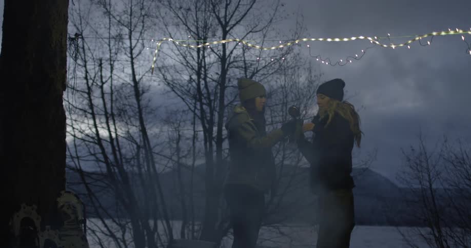 Two women talk and drink outside