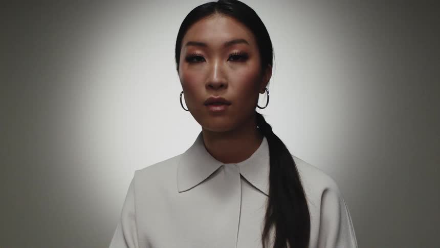 Woman with pony tail hoop earrings and white shirt looks at the camera