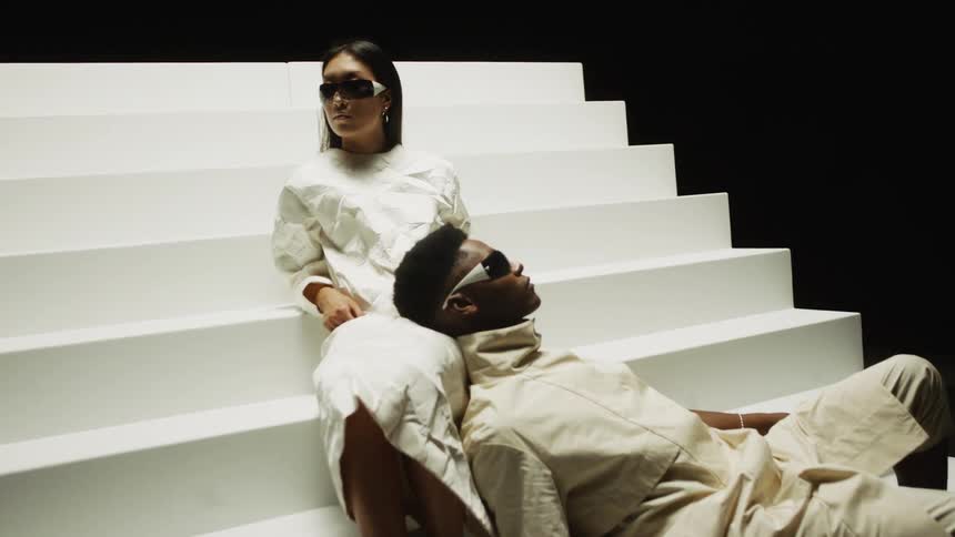 Two futuristic looking people sitting on white stairs
