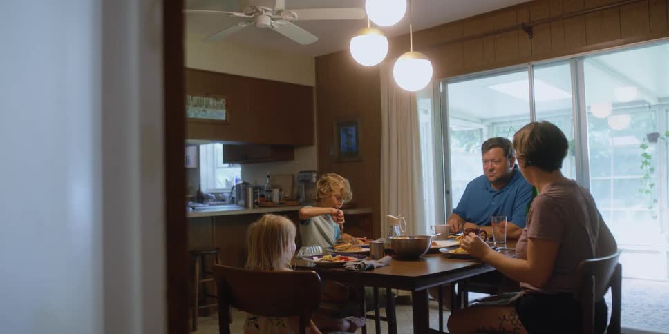 A family of four laugh over dinner at their kitchen table