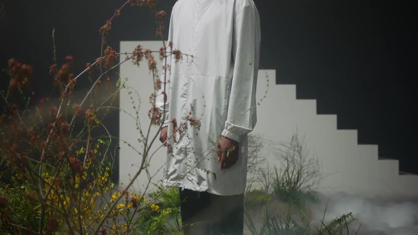 A person stands in a field in front of a staircase to nowhere