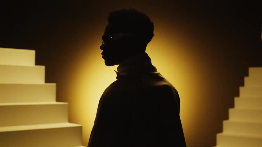A silhouette of a person standing in a dark room by stairs