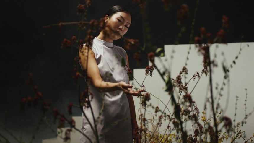 A woman is standing by a tree outdoors at night