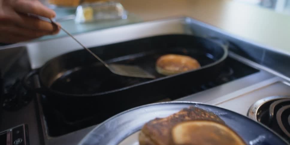 A woman is cooking pancakes on her stove