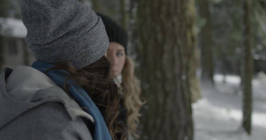 Two women stand in the woods and talk