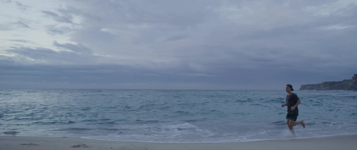 A man runs in the shallow beach water by the beach