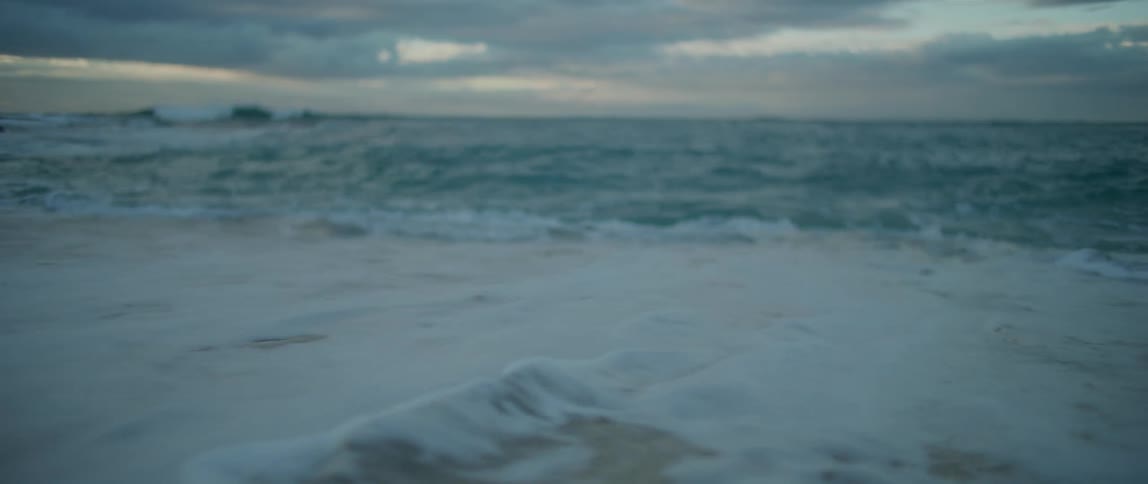 Waves rolling and splashing over a beach under a cloudy sky