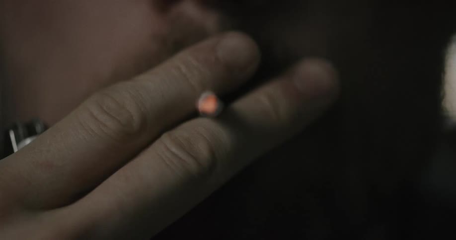 A man raises a lighter to light a rolled up paper in his mouth