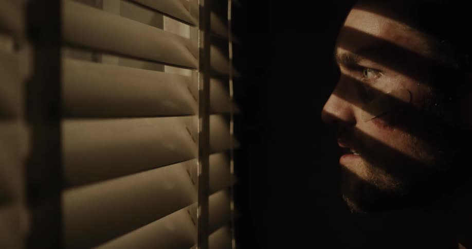 A man is looking through a window at night