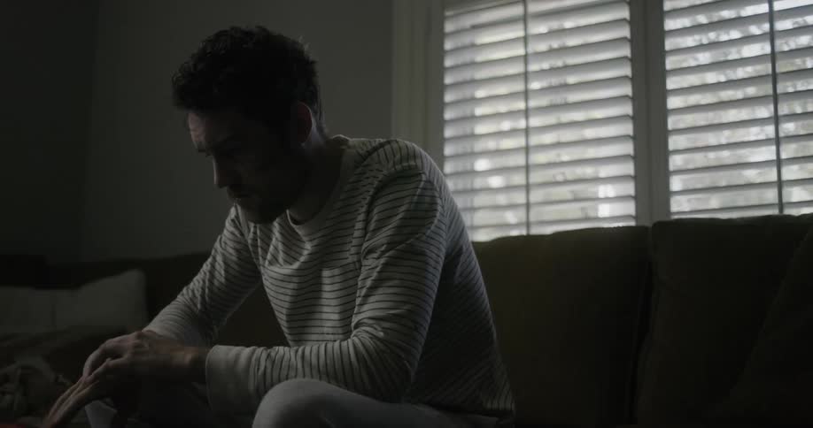 Man sitting in couch puts the phone over the coffee table after reading a message