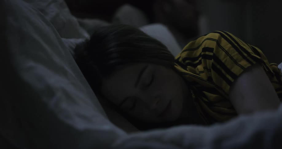 Woman with red and yellow shortsleeved shirt lies in bed to sleep in the bedroom at night
