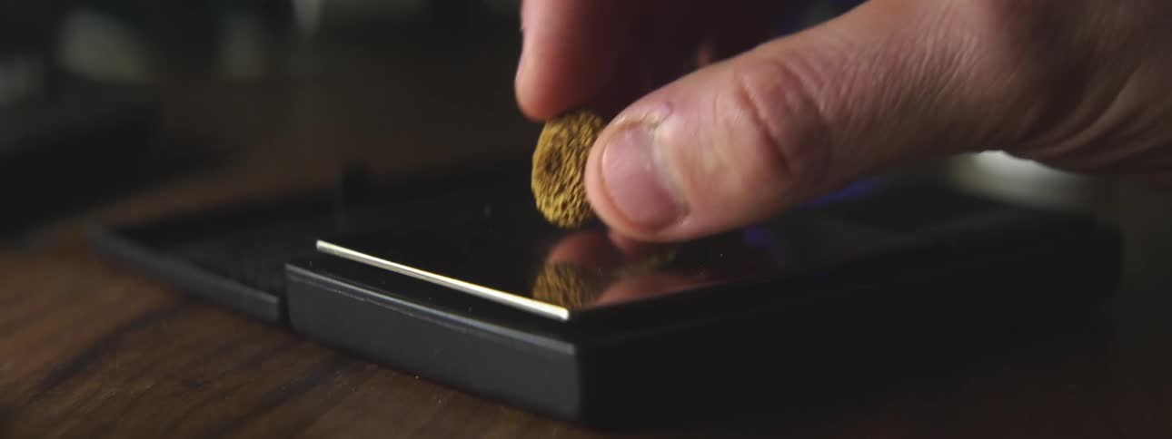 A person in a room placing a mushroom on a scale on a table
