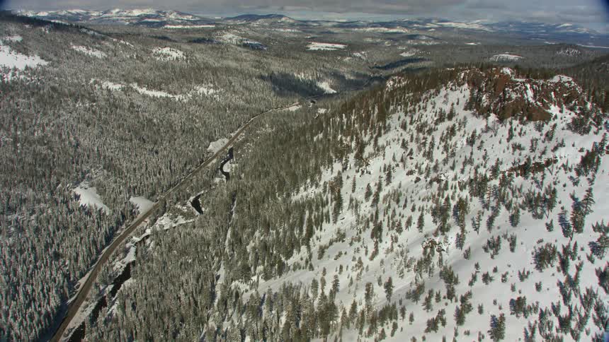 Snow covered mountain forests surrounding a road