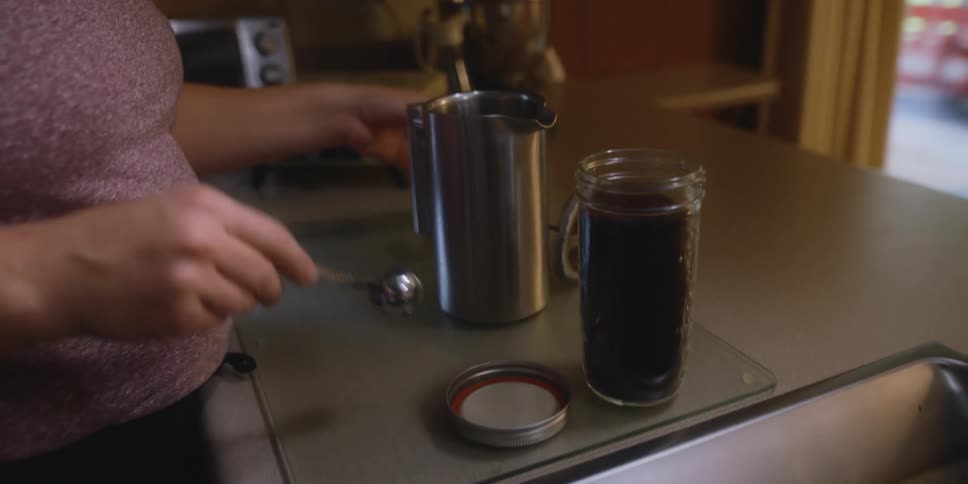 Woman preparing a pot of coffee on the kitchen counter top at home
