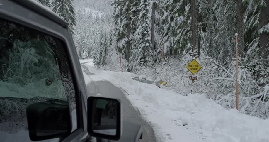 A truck is driving down a small road with snow all over
