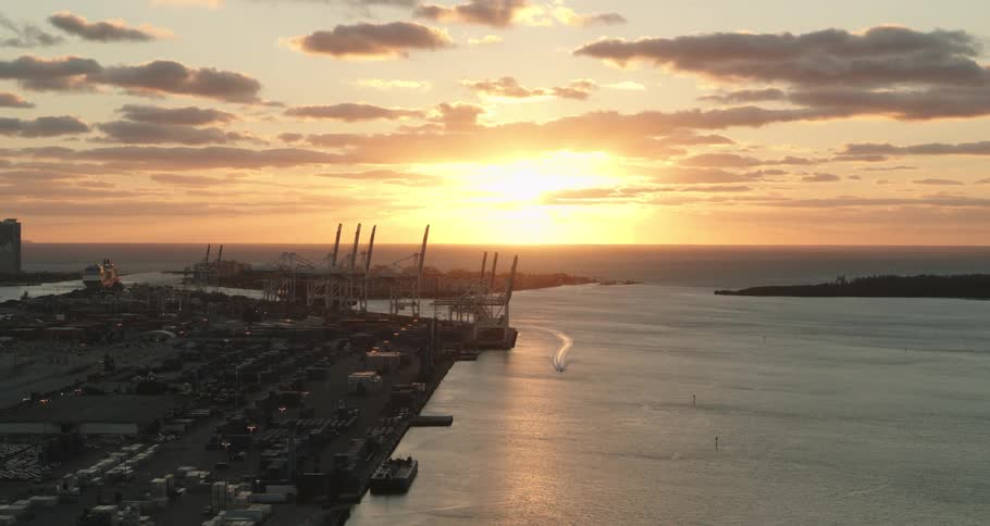 Beautiful sunset over a harbor as a boat sails across the water