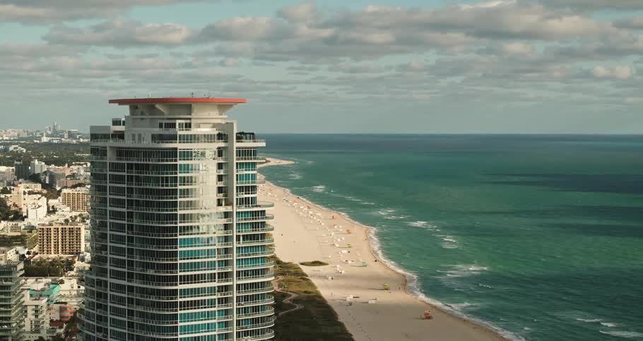 Aerial view of a tall skyscraper towering over a waterfront city next to the ocean