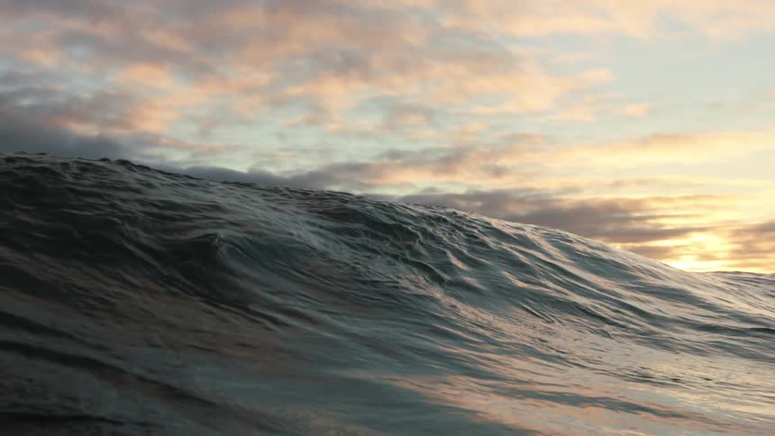 A wave moves over the water at sunset