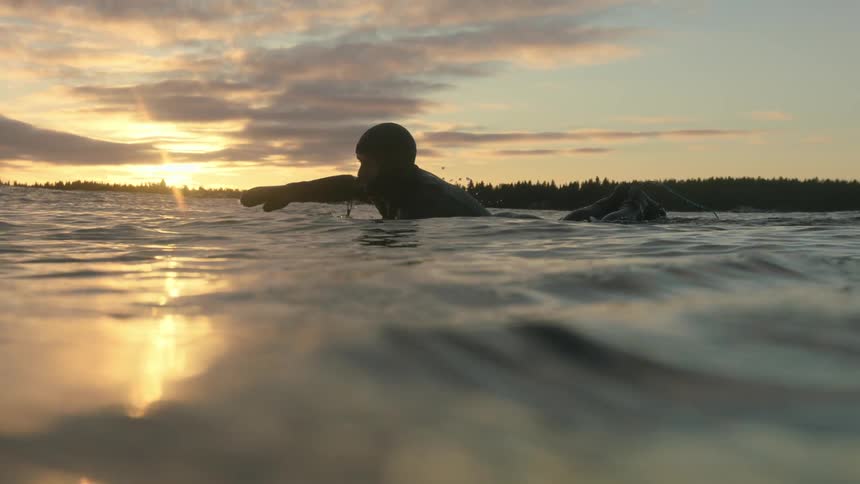 A man swims near sunset