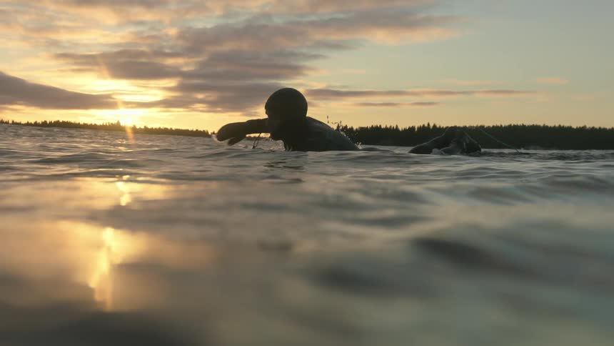 A man swims at sunset