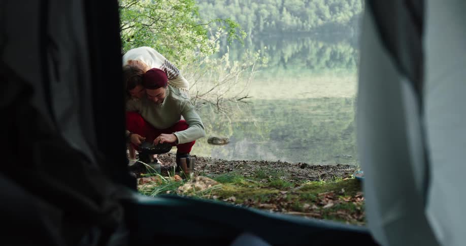 Young couple near a tent camping on a lake in the mountains