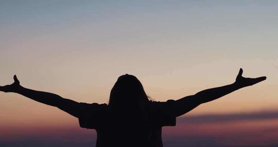 A woman is stretching outdoors at dusk