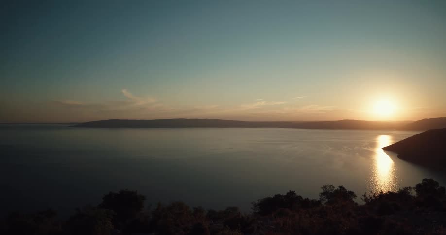 Sunset reflecting over the water in a bay and a few clouds in the sky