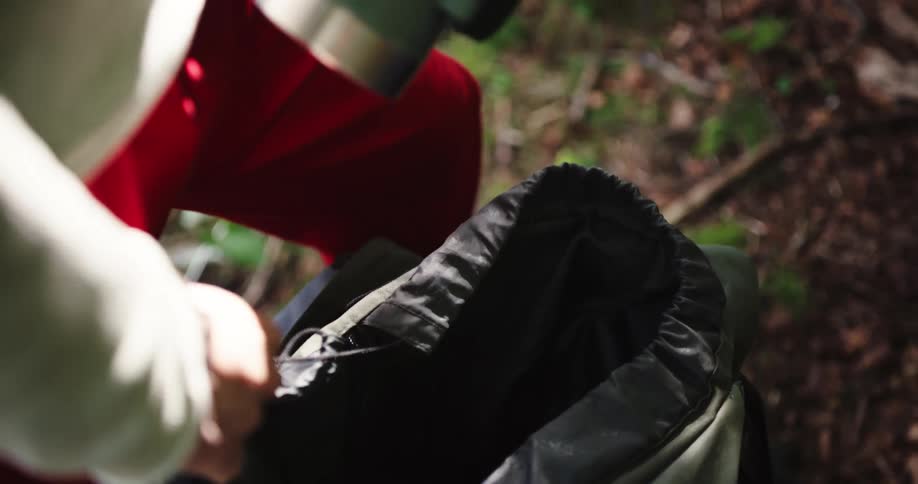 Person in the forest unpacking camping supplies from a backpack