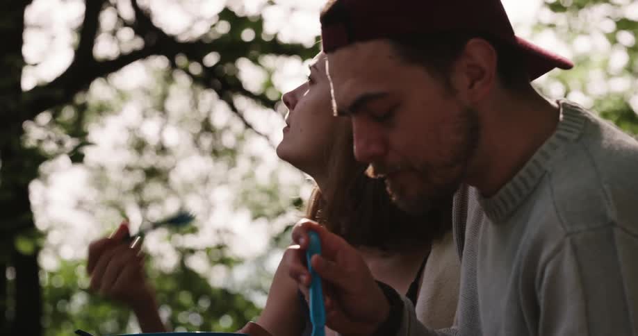 Couple sits outdoors eating and sharing food