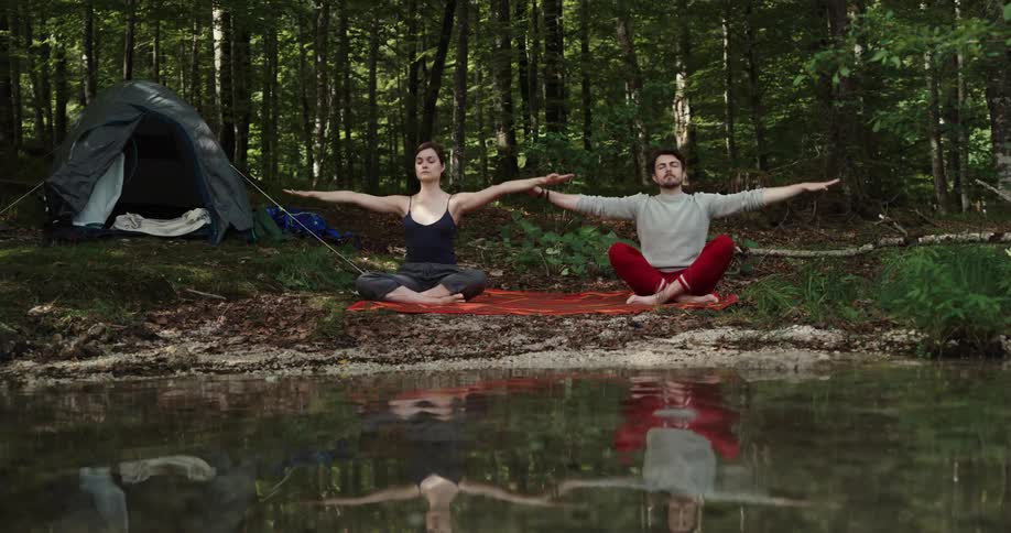 Man and woman are in the wilderness and doing yoga