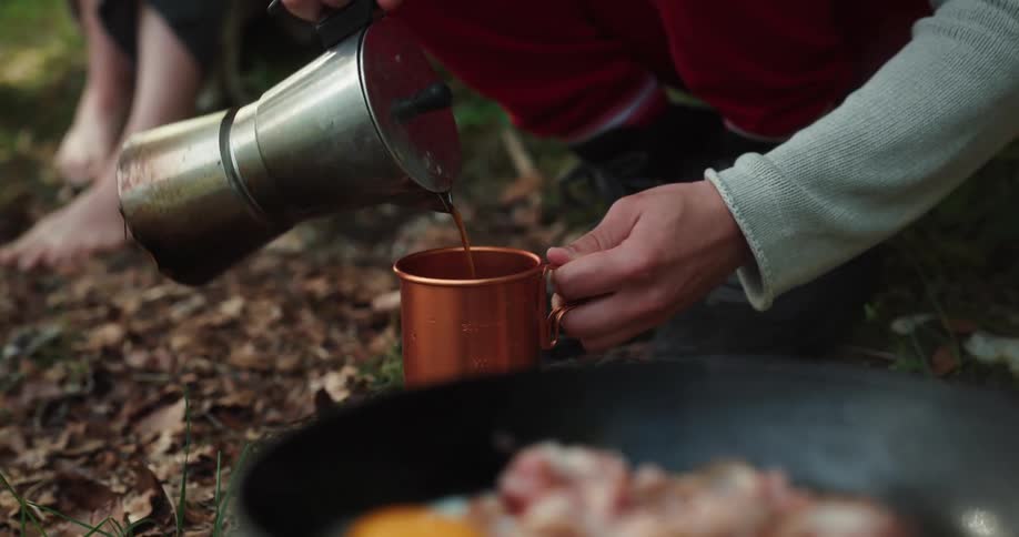 A man and woman are sitting outdoors at making food in the wilderness