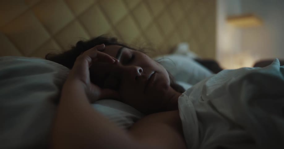 Woman sleeps in bed in the bedroom at night