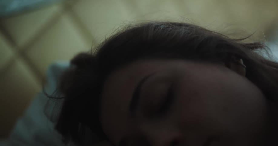 Waving hair of a woman sleeping in bed inside a dimly lit room