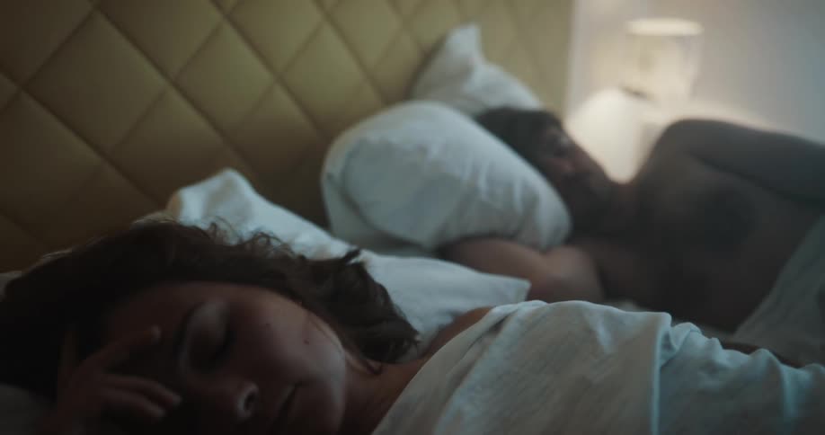 A man and woman are sleeping on a bed together
