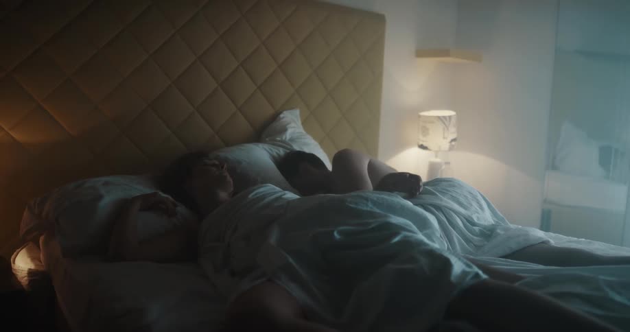 Man and woman asleep in bed begin to stir