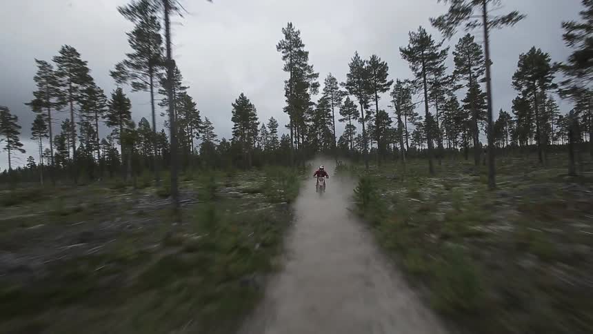A man is riding a motorbike down a dirt trail