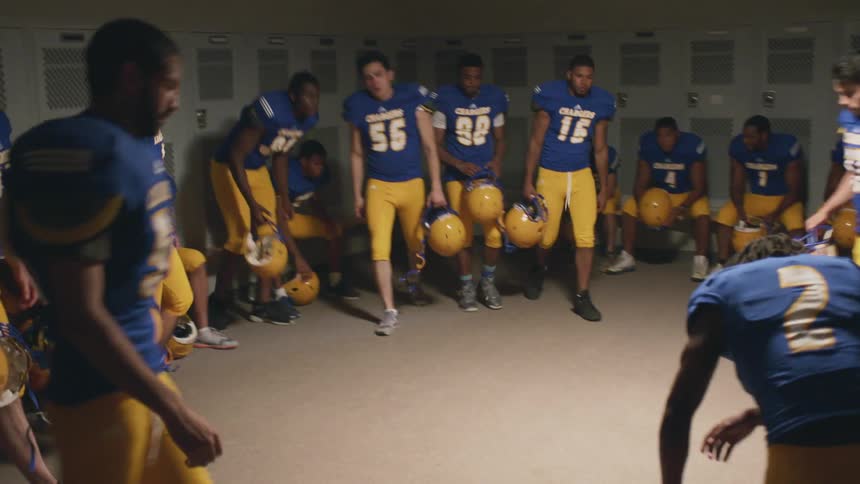 Young football players gathering for a huddle in a locker room