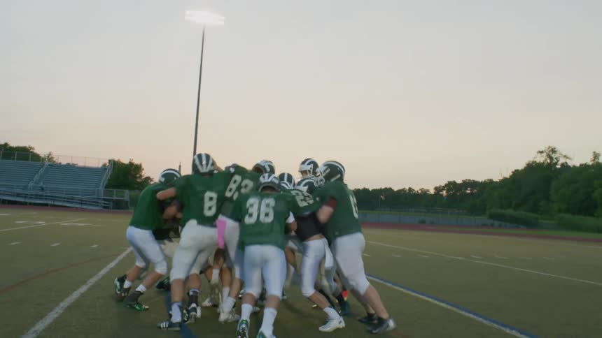A youth football team practices in the evening