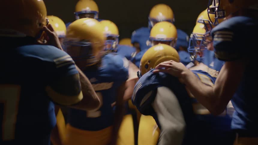 Members of a high school football pump themselves up for a game by jumping around