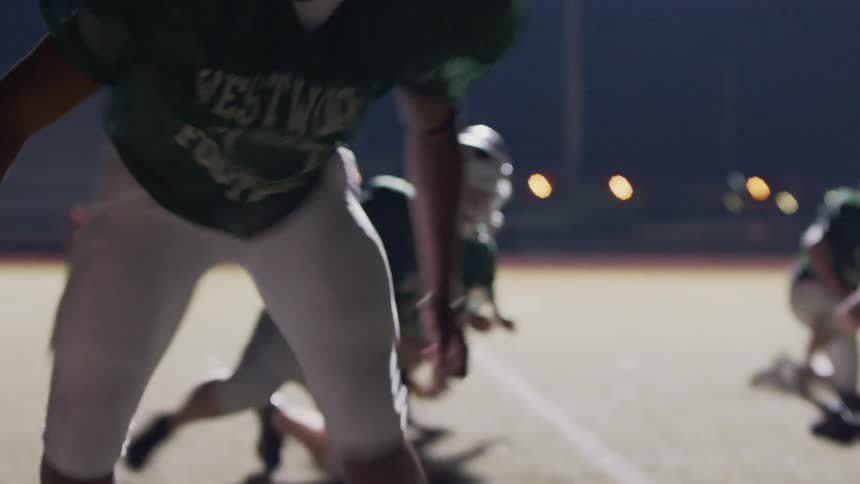 Football players training on a large field at night
