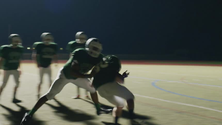 Football players practicing on a field at night