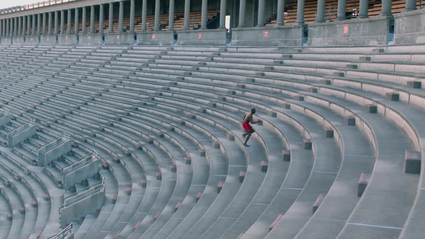 A man is running up the bleachers in a sports stadium