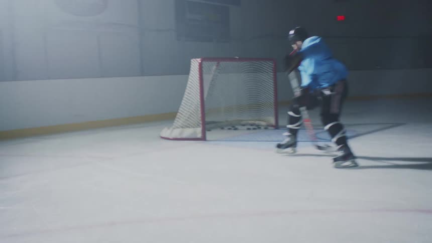 A hockey playing skating on an ice rink practicing his shots