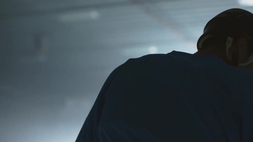 A hockey player standing in a dark stadium