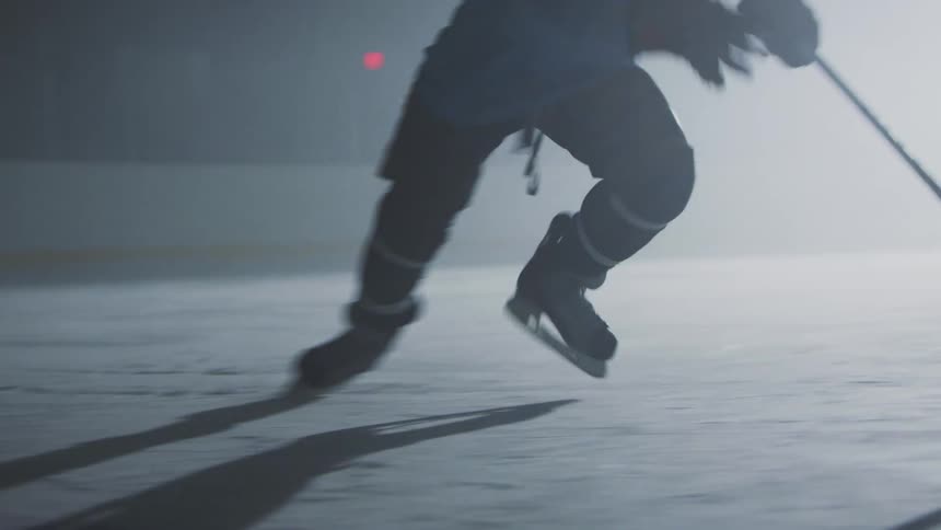 A hockey player is skating on a rink with a hockey stick